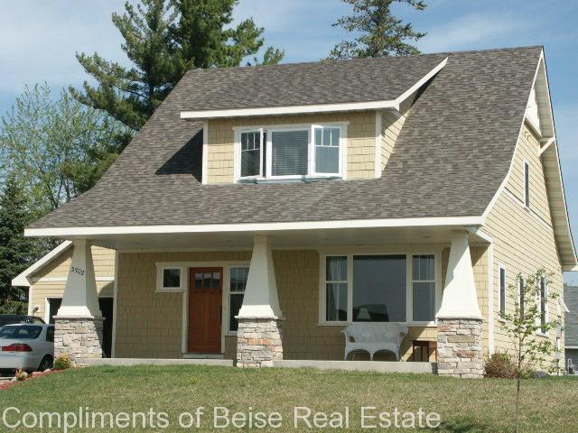 Charming two-story beige house at 3702 Pauly Farm Circle with a covered front porch, stone pillars, brown roof, and white trim. A car is partially visible in the driveway on the left. - Beise Real Estate