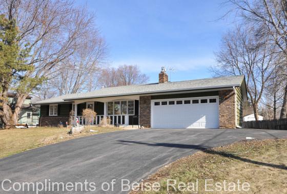 Charming single-story brick home at 4854 Drake Street features an attached two-car garage, inviting front porch, and a sloped driveway on a mostly bare yard dotted with sparse trees. - Beise Real Estate