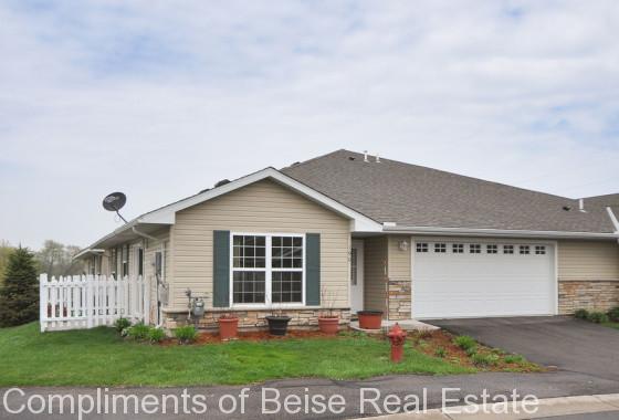 Charming single-story suburban house at 190 Kings Point with beige siding, green shutters, a white picket fence, two-car garage, and potted plants out front. Explore this gem in Kings Point real estate under an overcast sky. - Beise Real Estate