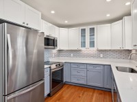 Modern kitchen at 4709 Utah Avenue with stainless steel appliances, white upper cabinets, light gray lower cabinets, subway tile backsplash, and hardwood flooring—perfect for stylish New Hope living. - Beise Real Estate