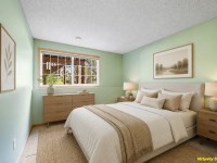 Bedroom with green walls, large window, bed with beige bedding, wooden nightstands and dresser, lamps, framed art, and "Virtually Staged" text in the bottom right corner—located on Wiedman Way in Eden Prairie. - Beise Real Estate