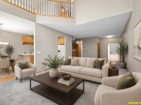 Spacious living room with beige walls, modern furniture, coffee table, and large rug, open to dining area—located on Wiedman Way in Eden Prairie; "Virtually Staged" text in lower right corner. - Beise Real Estate