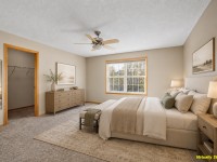 A bedroom on Wiedman Way in Eden Prairie features a large window, bed, two nightstands, a dresser, ceiling fan, and walk-in closet. The room is virtually staged, as noted in the corner. - Beise Real Estate