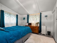 Bedroom on Rainbow Avenue with teal bedding, wooden dresser, white rug, teal curtains, floral wall decals, and natural light pouring through windows—perfect for a cozy Maple Plain retreat. - Beise Real Estate