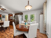 A kitchen and dining area in Maple Plain with a round wooden table, four white upholstered chairs, stainless steel appliances, and French doors leading outside to Rainbow Avenue. - Beise Real Estate